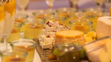 Una mesa con diversos alimentos, incluyendo queso y postres, dispuesta para una reunión.