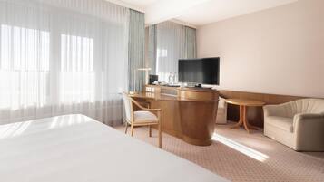 Ein Hotelzimmer mit einem Bett, einem Schreibtisch mit Fernseher, einem Sessel und einem Sofa.