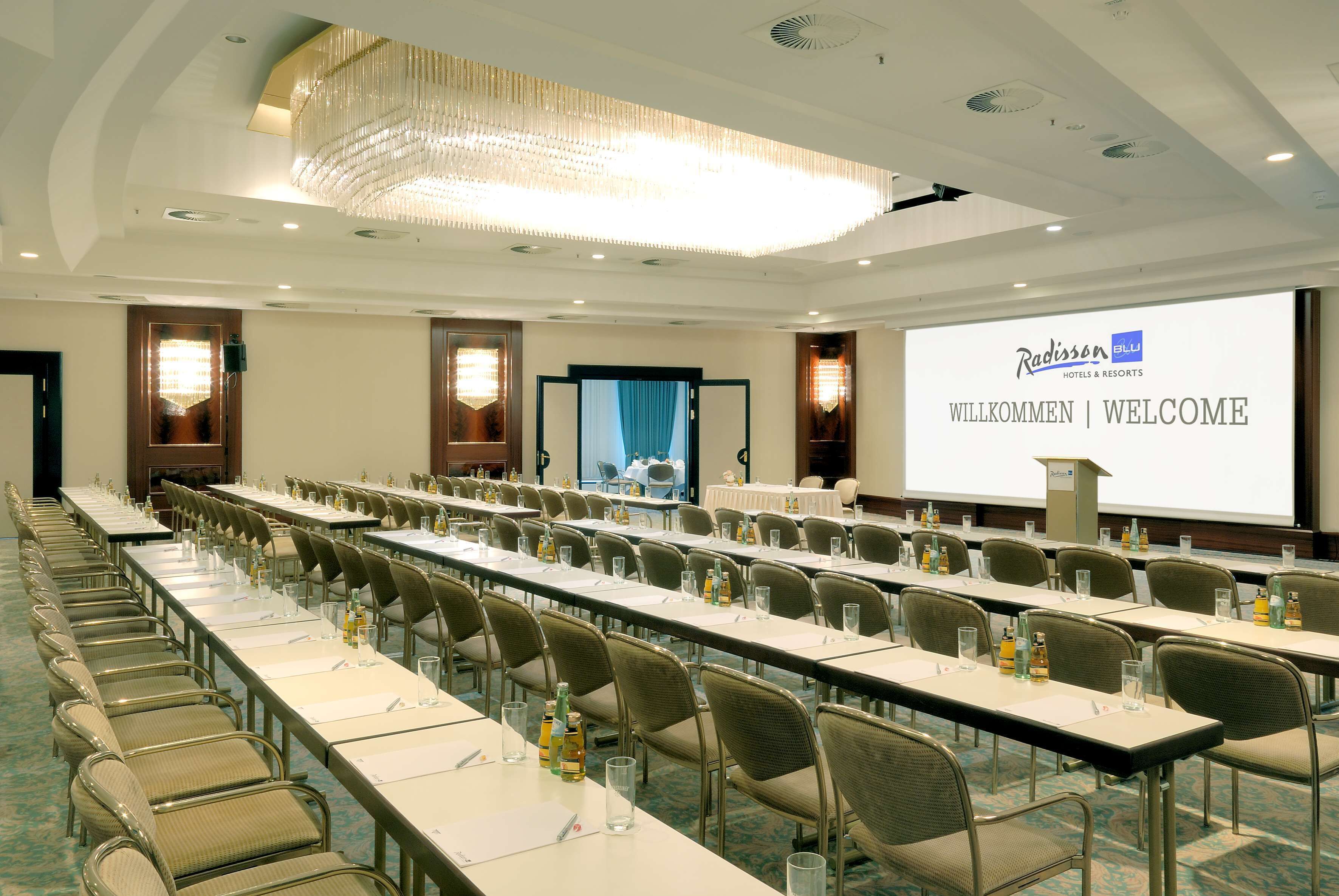 A conference room with long tables, chairs, and a projector screen displaying "Radisson Hotels & Resorts" and "WELCOME".