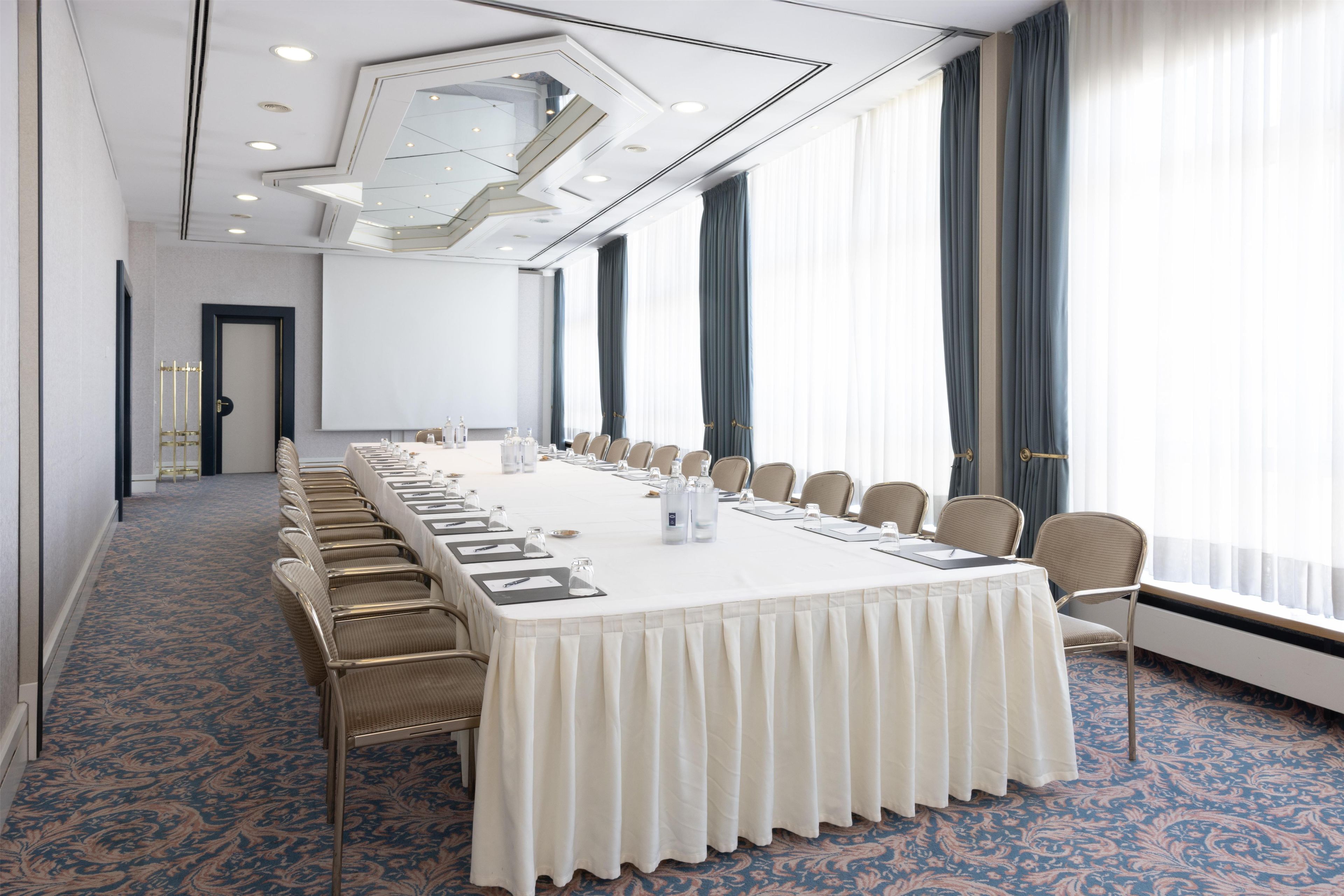 A conference room with a long table, chairs, and a carpeted floor.