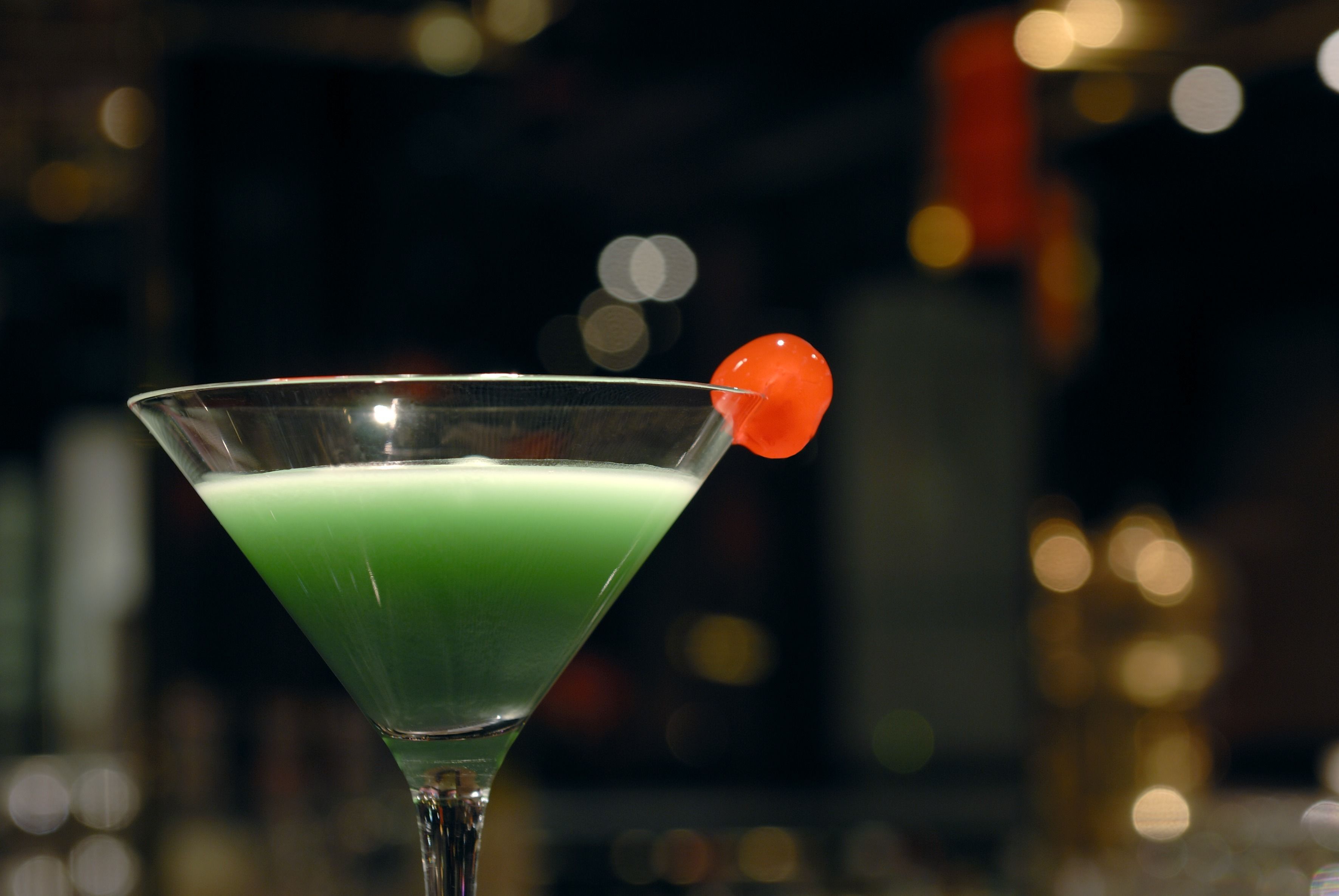 Ein Martini-Glas mit grüner Flüssigkeit und einer roten Garnitur.