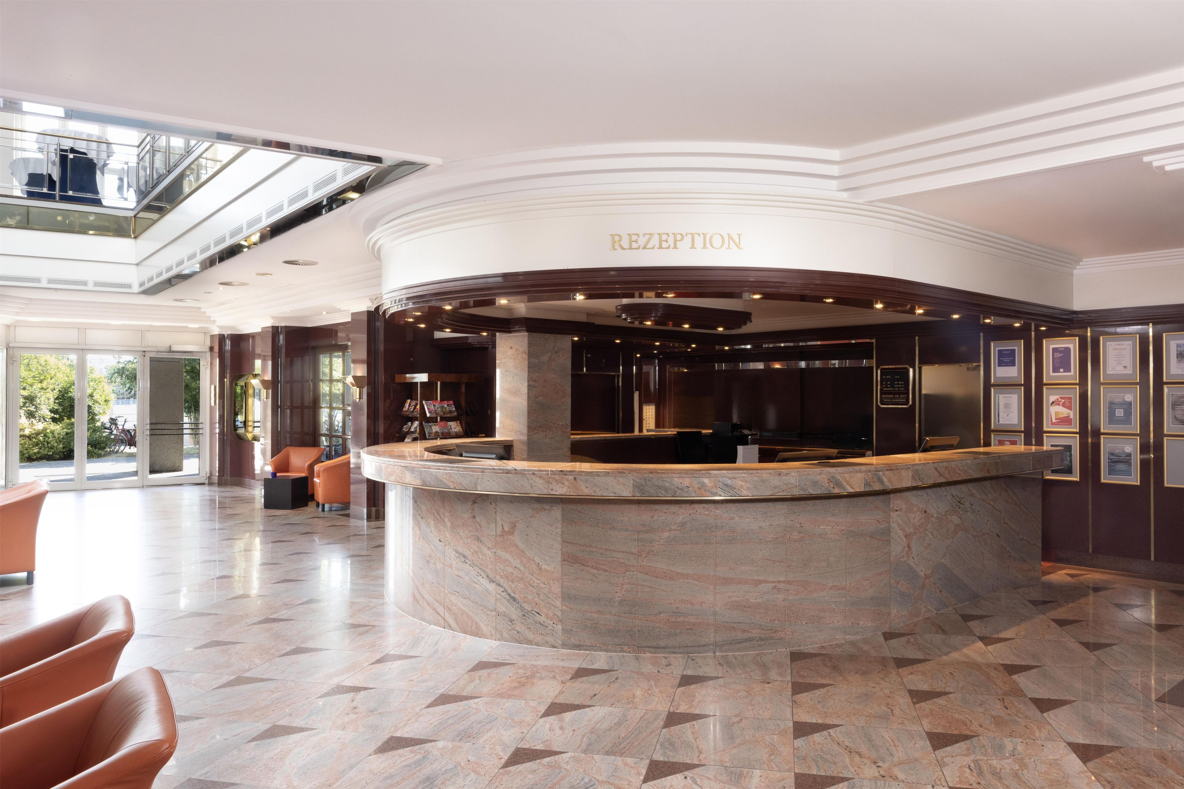 A reception area with a marble counter, a glass elevator, and a view of the outdoors.