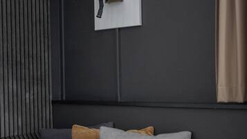 Camera da letto moderna con una parete scura, una lampada da comodino e un letto con biancheria a righe e tre cuscini.