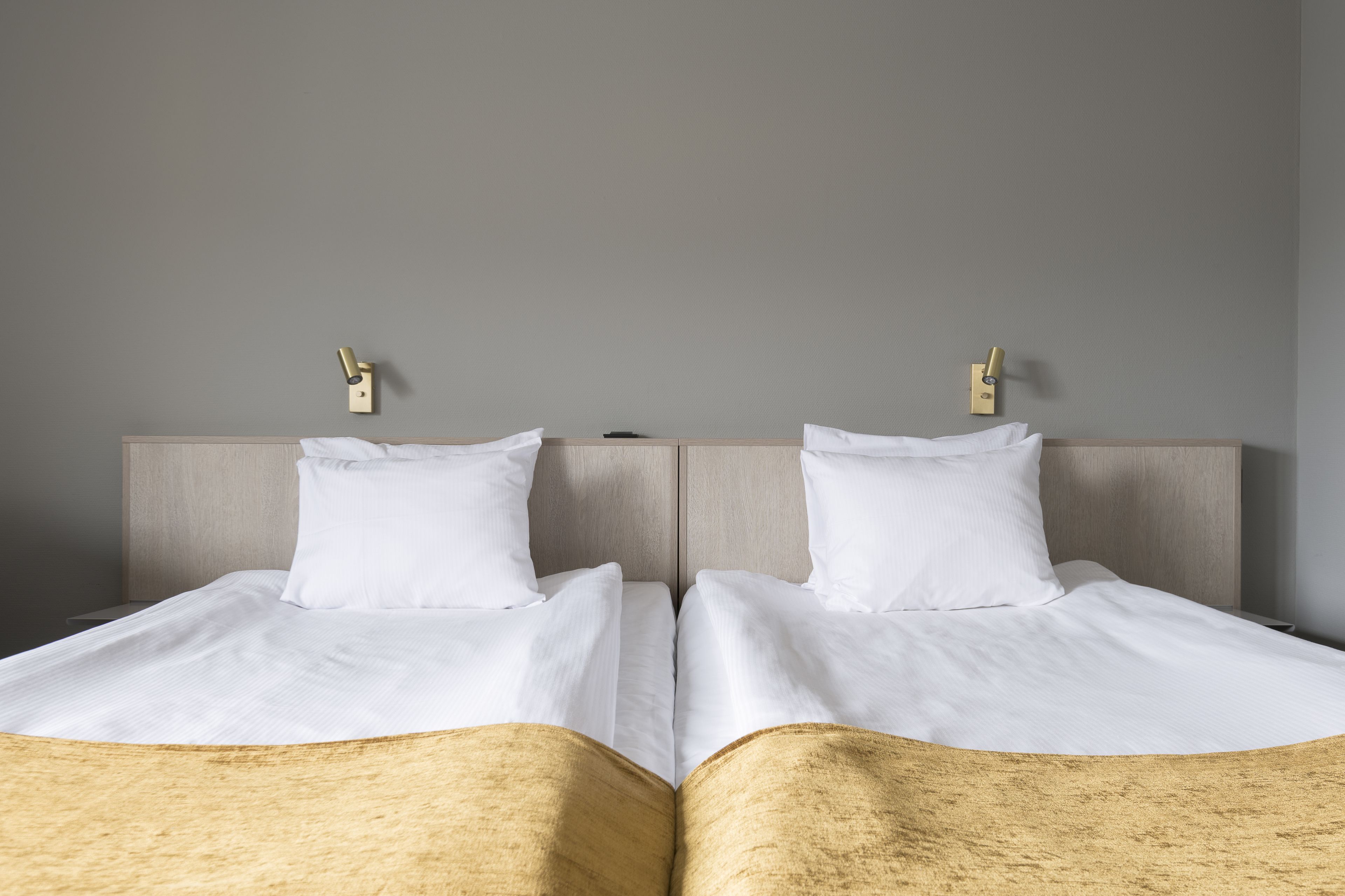 Un lit double avec du linge de lit blanc et une tête de lit en bois.