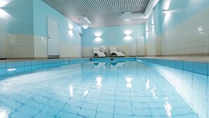 A swimming pool with tiled walls and ceiling, two lounge chairs, and a door. - Quality Hotel Royal Corner (Växjö)