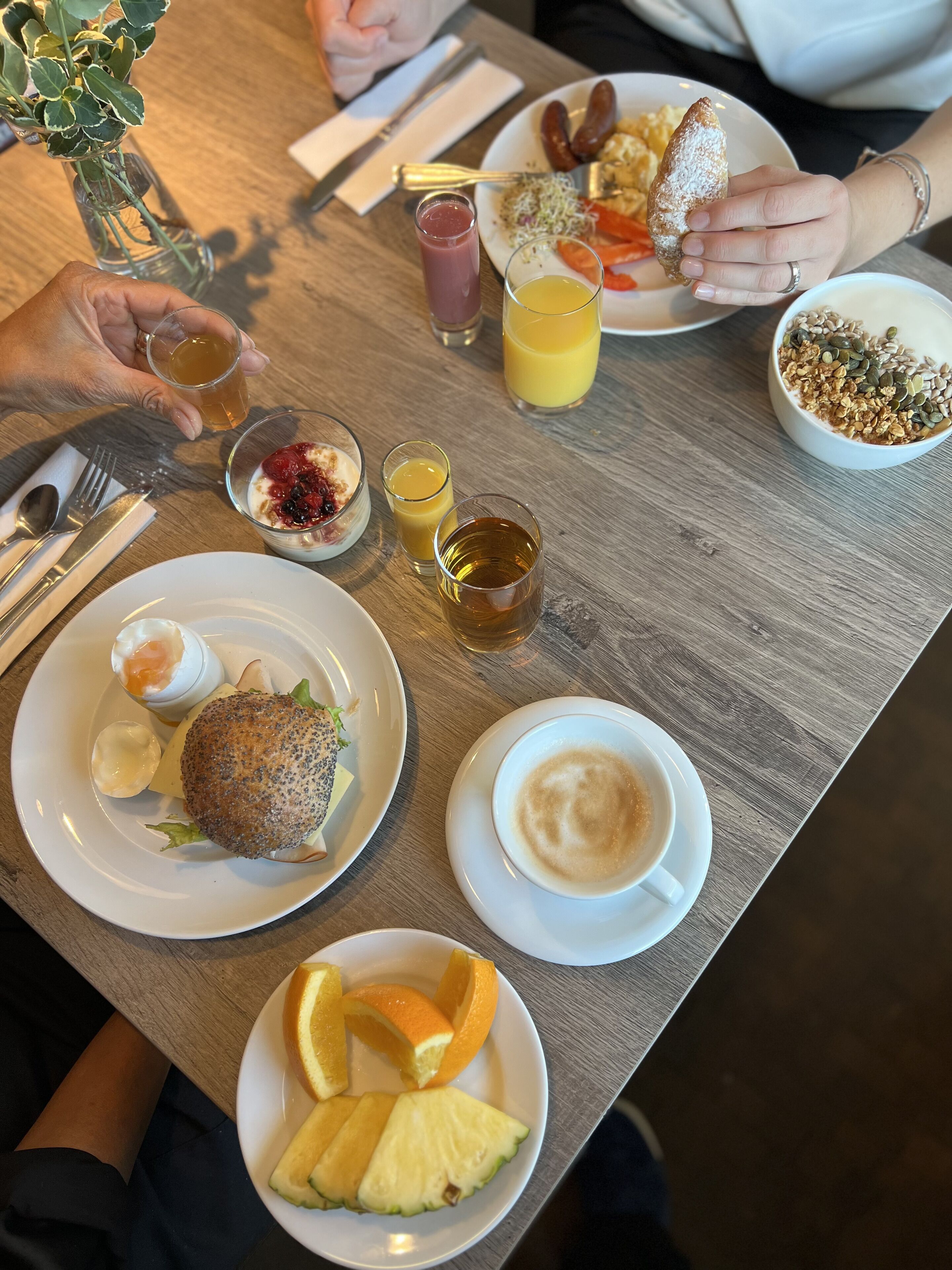 Une table à manger avec divers aliments pour le petit-déjeuner, notamment un sandwich, des fruits et des boissons.