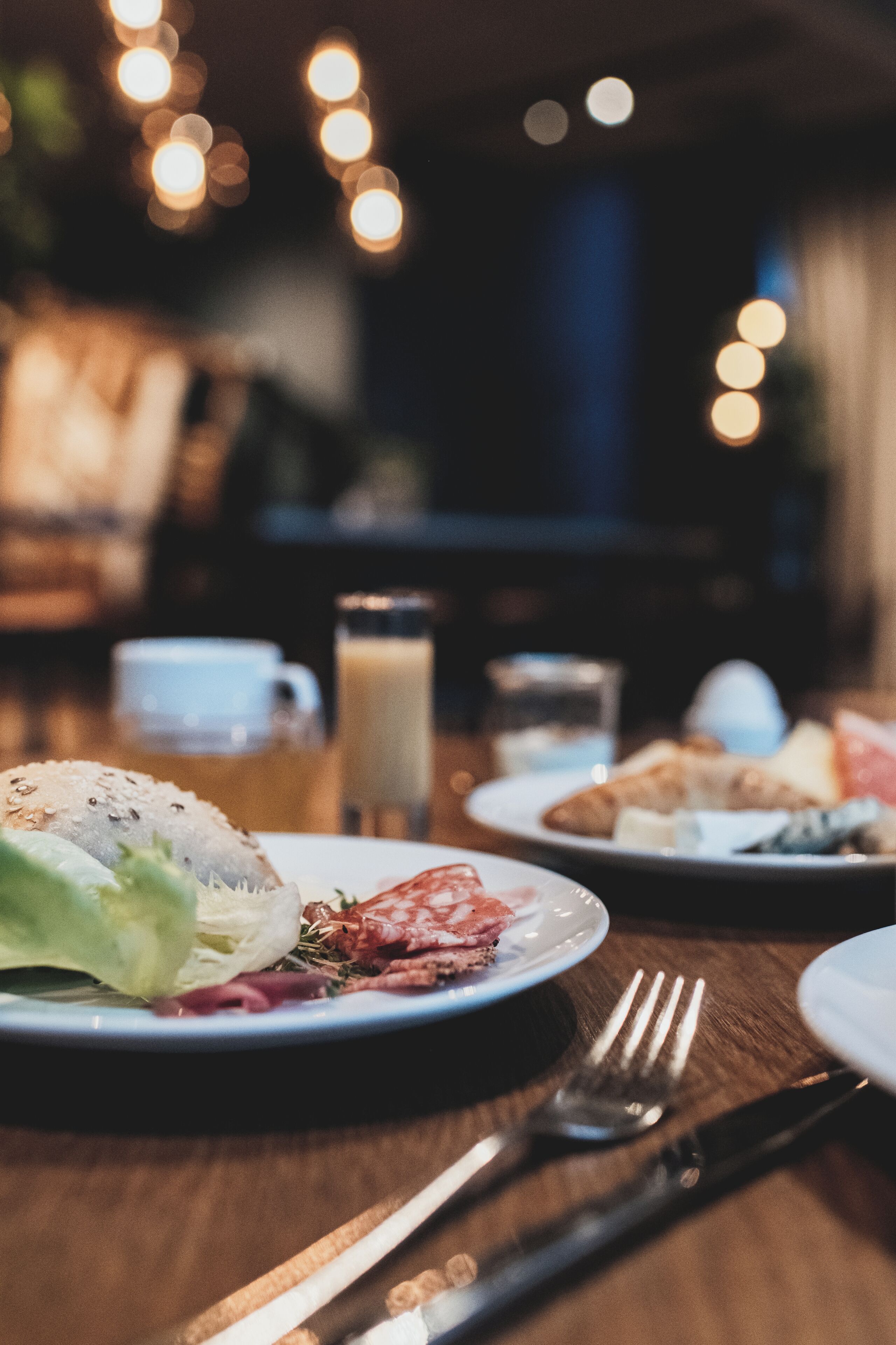 A dining table with plates of food, a glass of milk, and a cup.