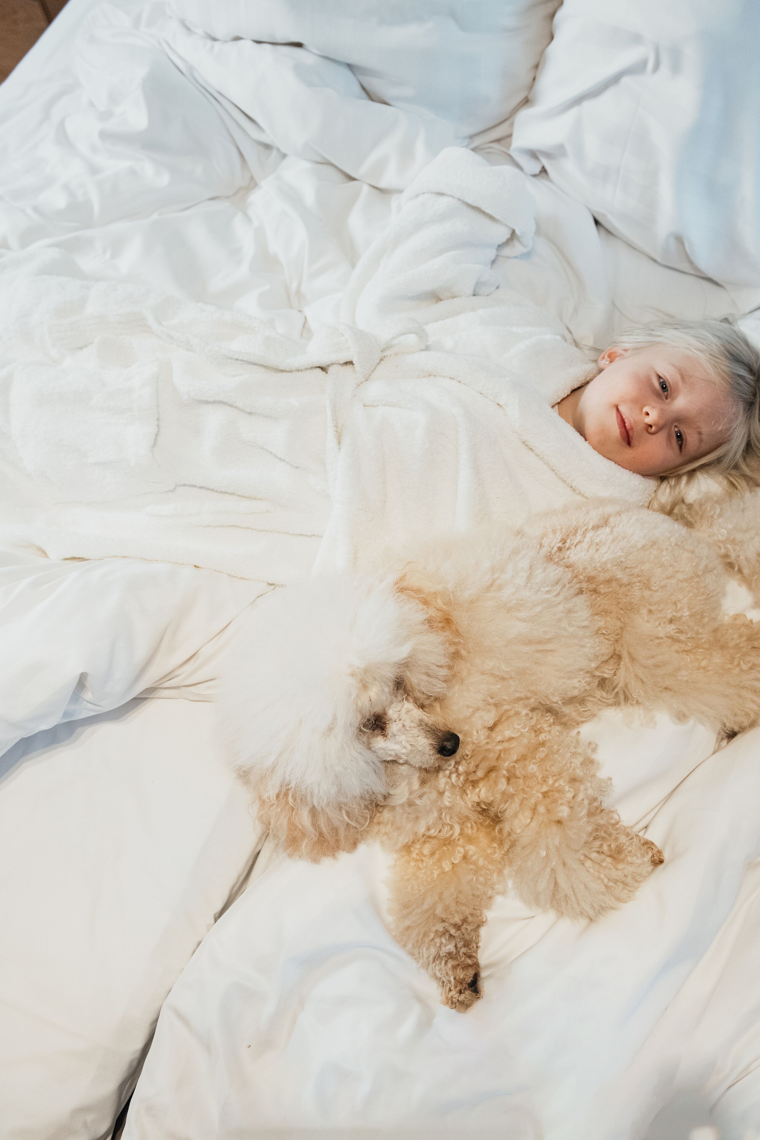 Una persona acostada en la cama con un perro esponjoso.
