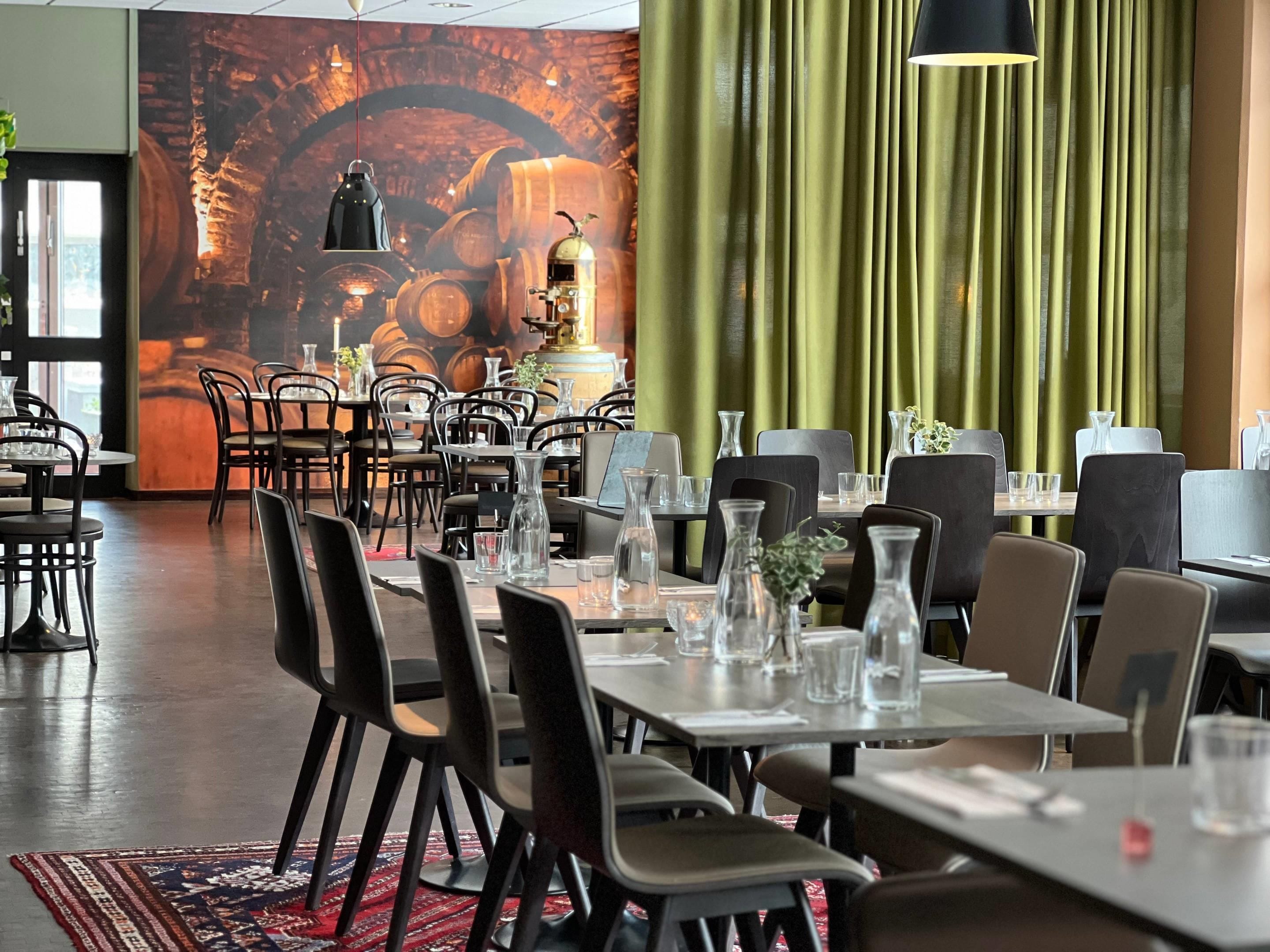 A restaurant interior with tables, chairs, and a mural of barrels.
