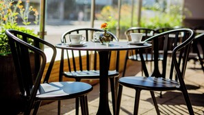 A round table with four chairs, a vase with a flower, and two cups on a terrace with a view of greenery and buildings. - Quality Hotel Royal Corner (Växjö)