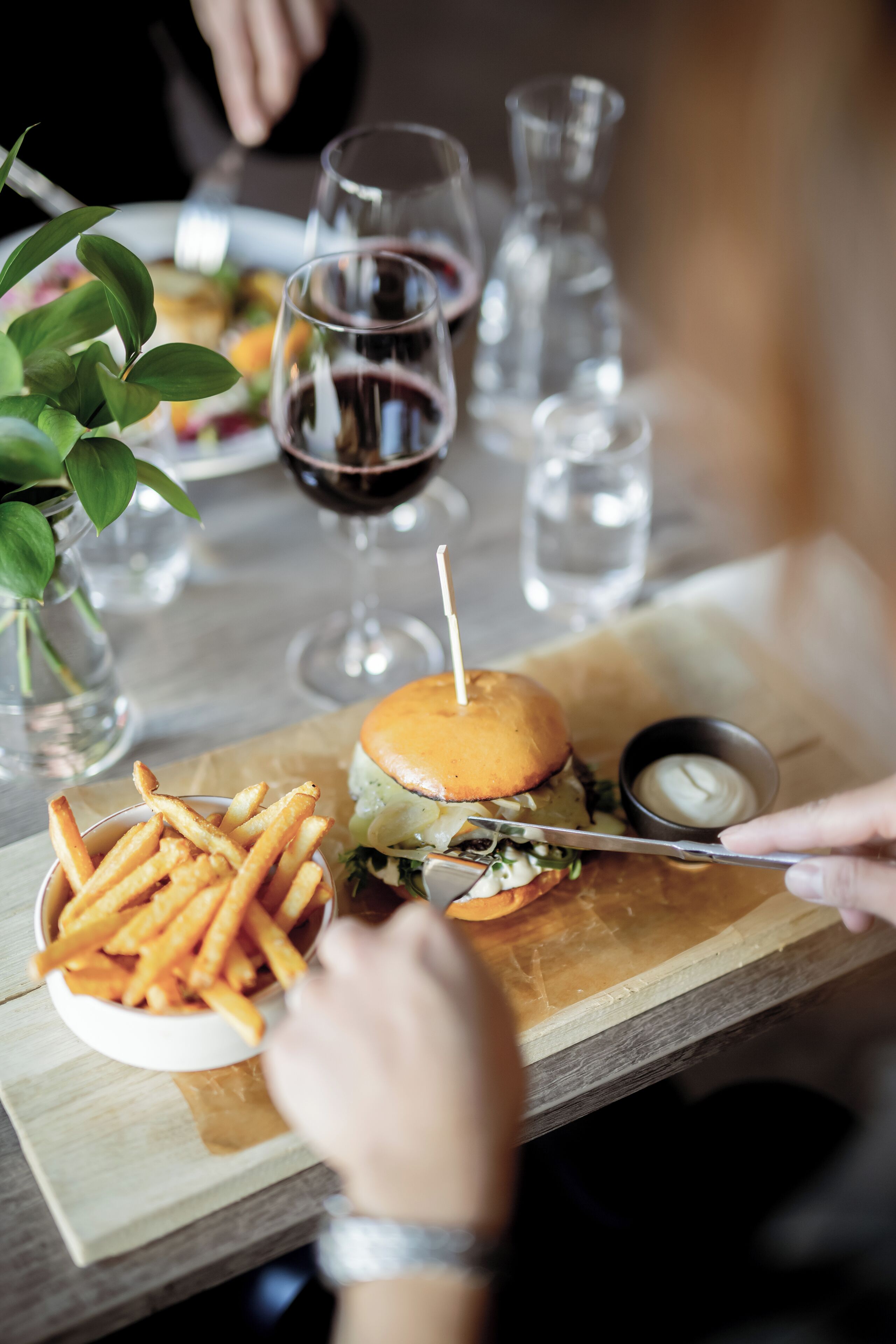 A dining table with a burger, fries, and a drink.