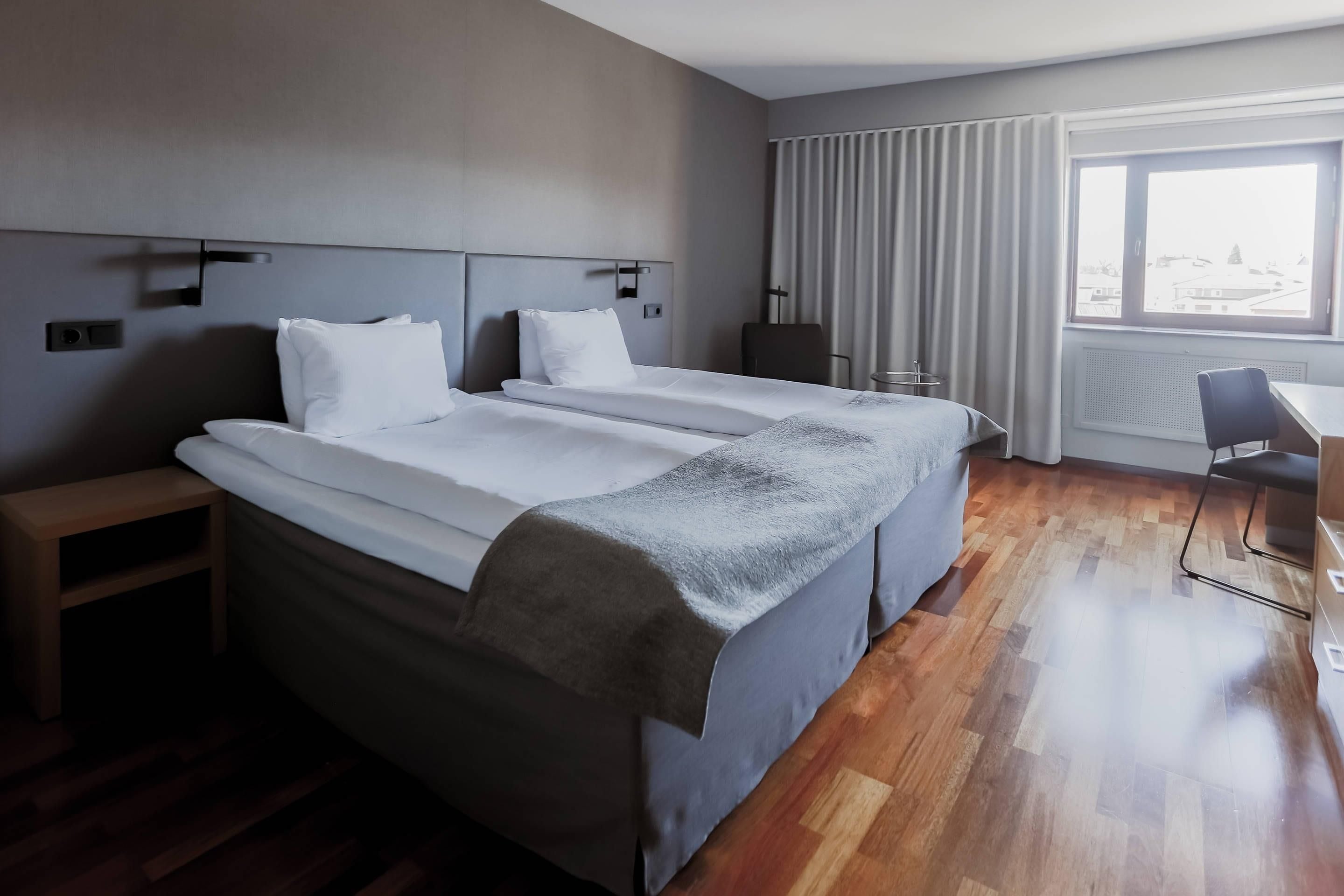 A hotel room with a large bed, a desk, and a chair.