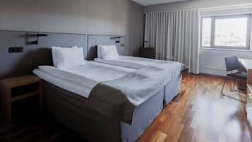 A hotel room with a large bed, a desk, and a chair.