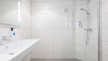 Un baño moderno con lavamanos, espejo y ducha blancos.