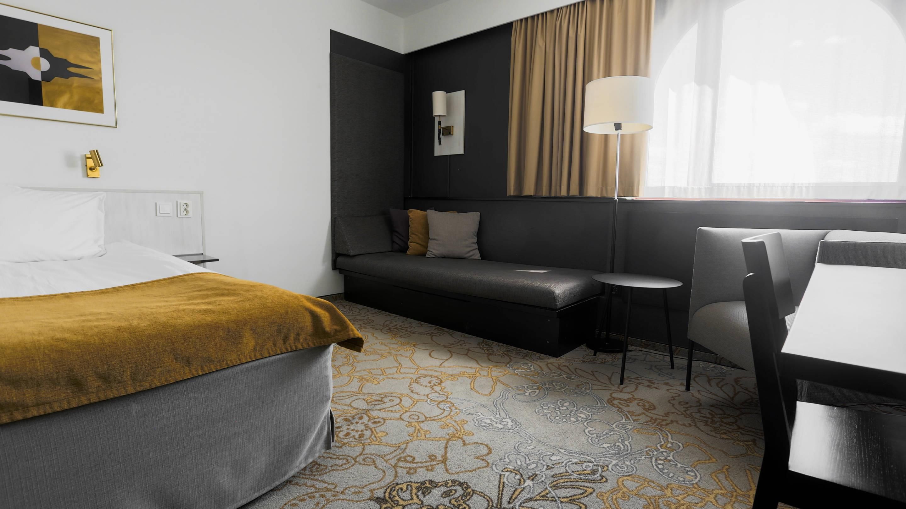 Une chambre d’hôtel avec un lit, un canapé, une petite table et une chaise.