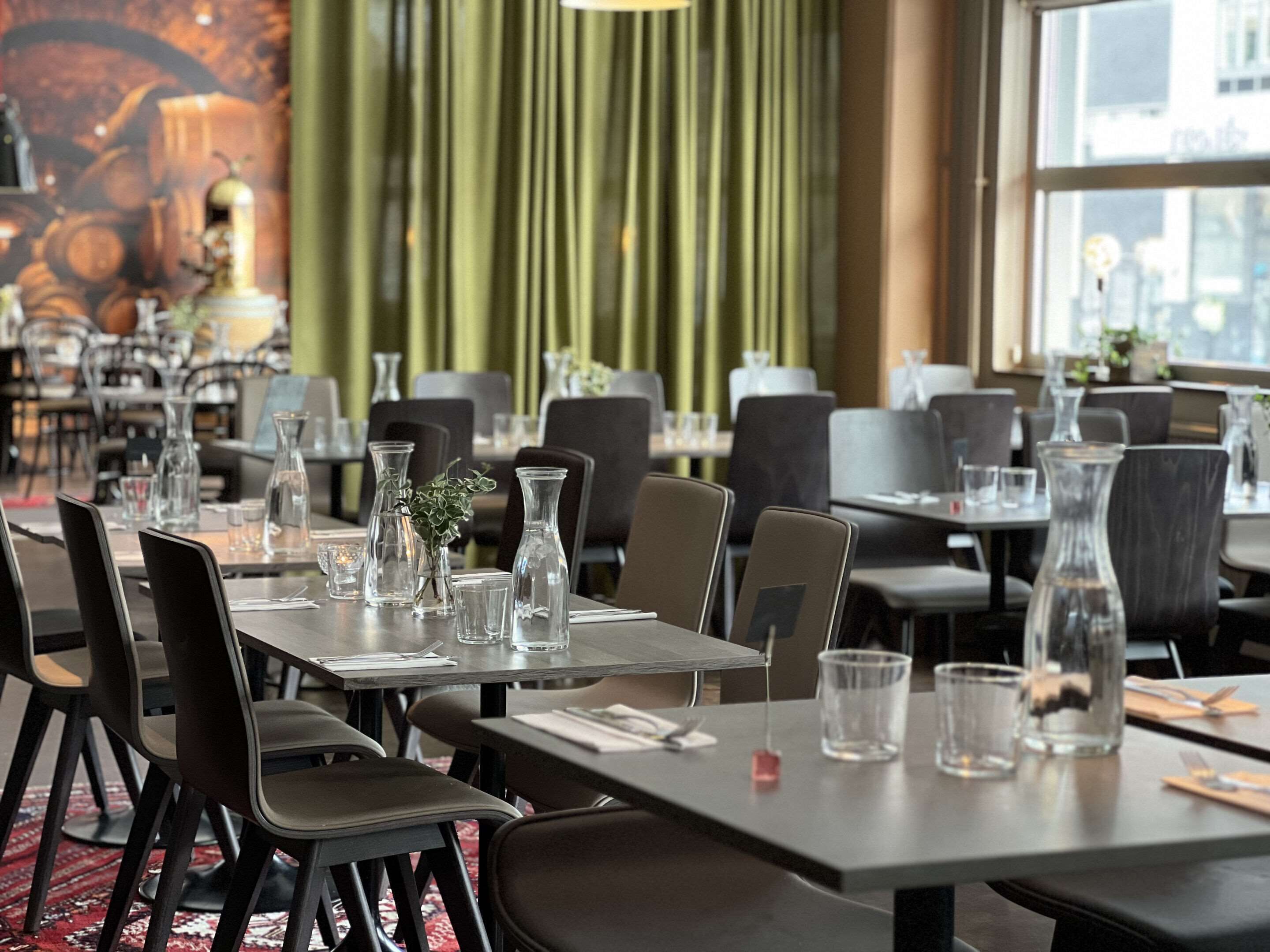 Un restaurante con mesas dispuestas para comer, sillas y jarrones decorativos.