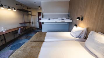 Een hotelkamer met een bed, een bureau, een stoel, een hanglamp en een wandlamp.