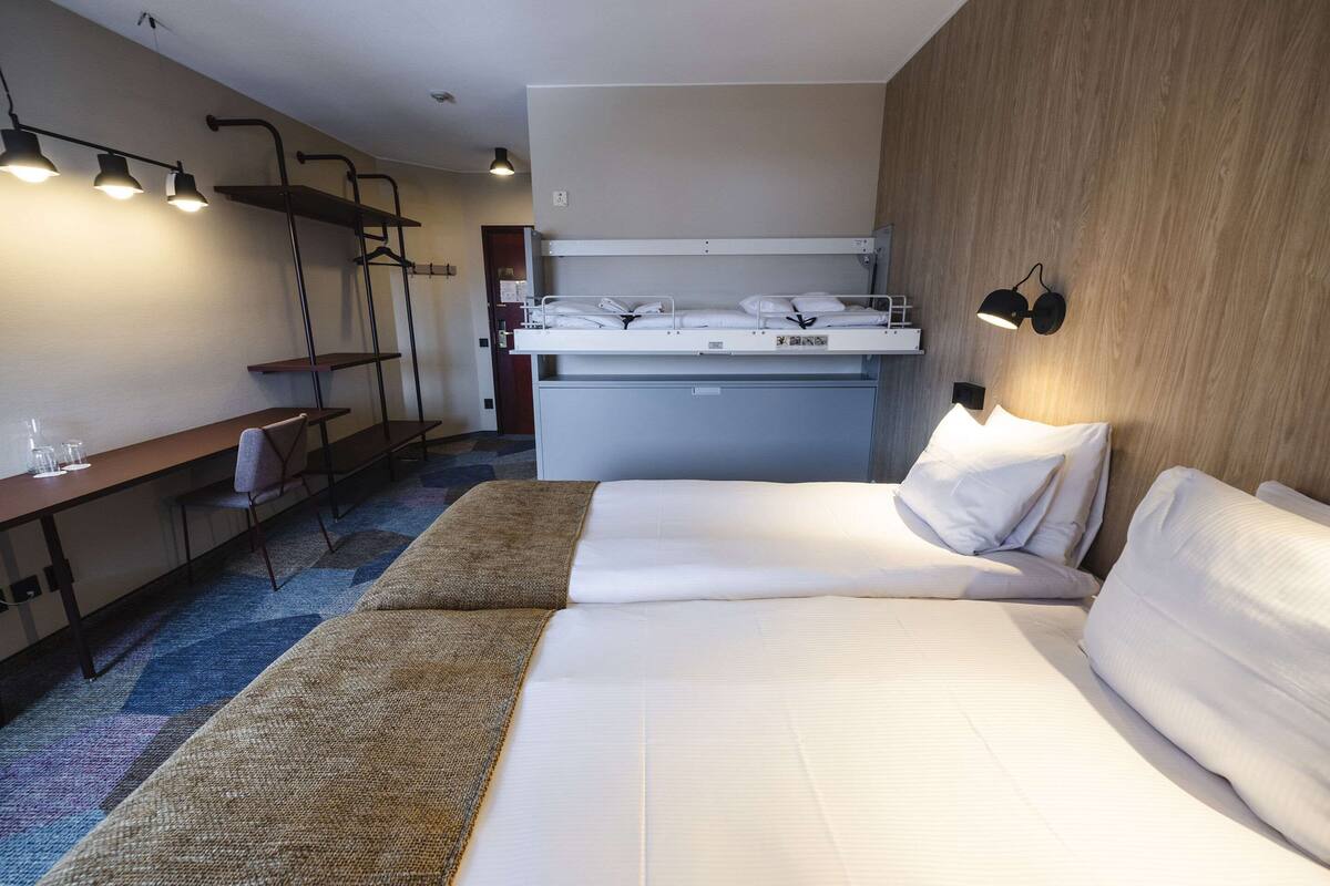 A hotel room with a bed, a desk, and a wardrobe.