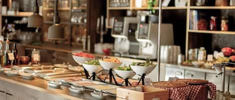 A buffet setup with various food items, a coffee machine, and a modern interior design.