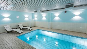 Una piscina techada, sillones reclinables de piscina