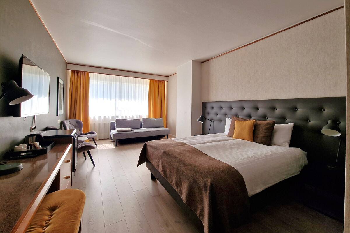 Ein Hotelzimmer mit einem großen Bett, einer Couch, einem Schreibtisch und einem Stuhl.