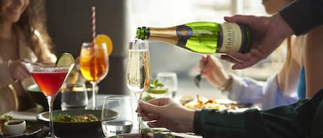 A dining table with various dishes, glasses, and a bottle of champagne being poured.