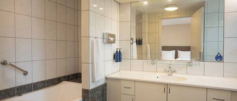 A modern bathroom with a bathtub, a sink, and a large mirror.