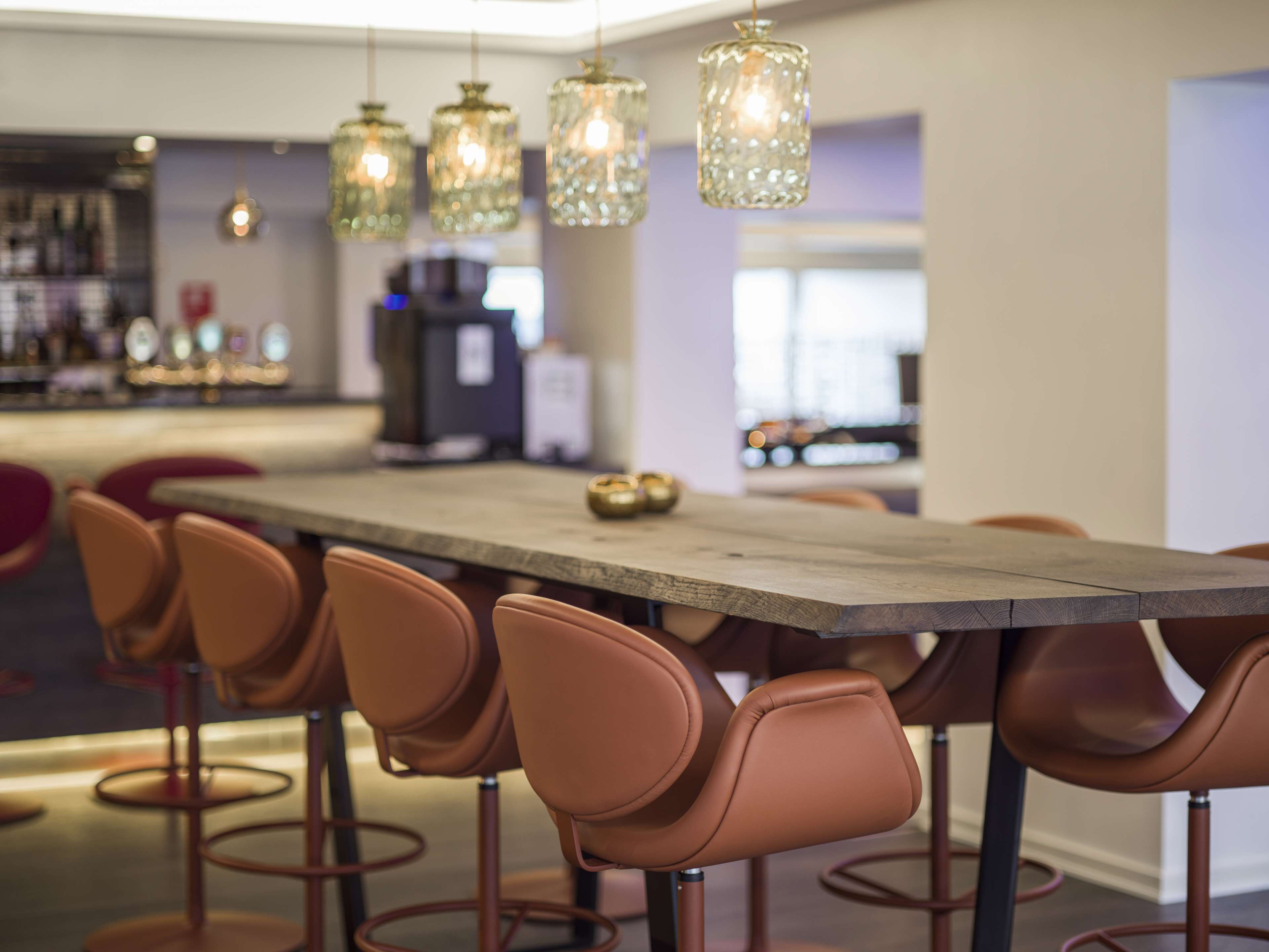Un comedor moderno con una mesa de madera grande y varios taburetes de bar.