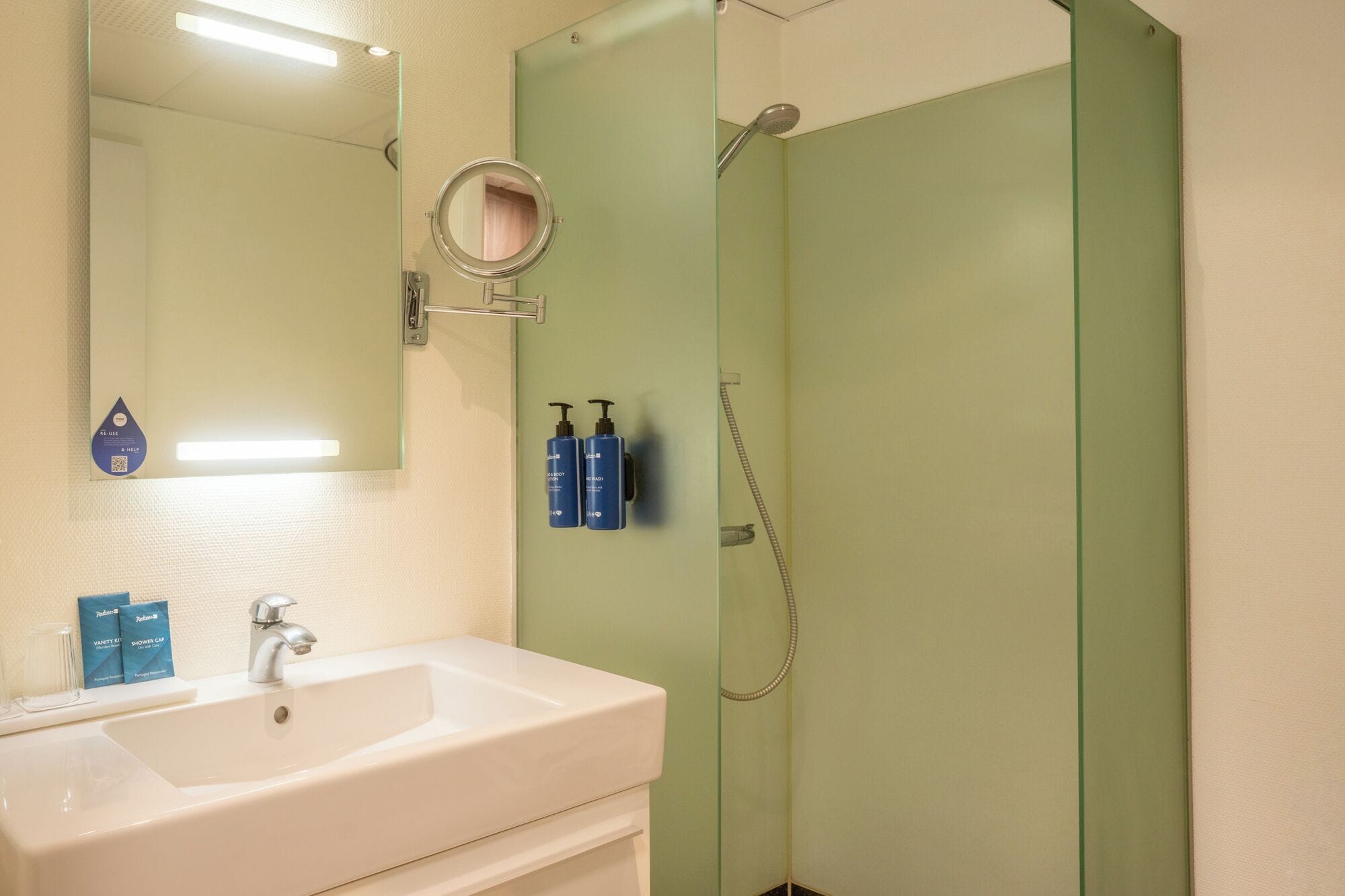 A bathroom with a white sink, a mirror, and a glass shower enclosure.