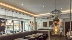 A modern restaurant with a long counter, multiple tables, and hanging pendant lights. - Radisson Blu Limfjord Hotel Aalborg (Aalborg)