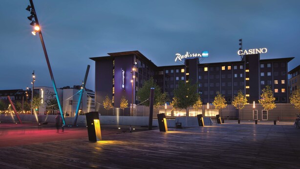 A modern building with "Radisson" and "CASINO" signage, surrounded by trees and a wooden deck. - Radisson Blu Limfjord Hotel Aalborg (Aalborg)