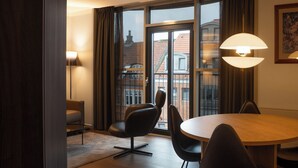 A modern room with a dining table, chairs, a sofa, and a large window with curtains. - Radisson Blu Limfjord Hotel Aalborg (Aalborg)