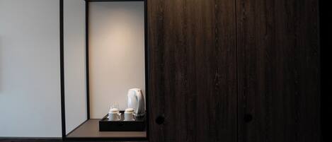 A modern bathroom with a dark wood vanity, a mirror, and a tray with a kettle and cups.