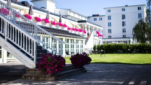 A building with a white facade, a staircase with white railings, and pink flowers. - Scandic Lillehammer Hotel (Lillehammer)