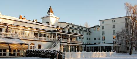A large, multi-story hotel with a prominent tower, multiple balconies, and a snow-covered courtyard.