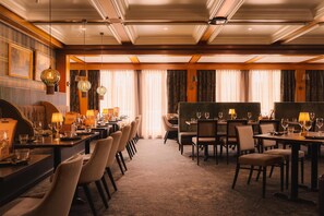 A hotel dining area with multiple tables and chairs, chandeliers, and framed artwork on the walls. - Scandic Lillehammer Hotel (Lillehammer)