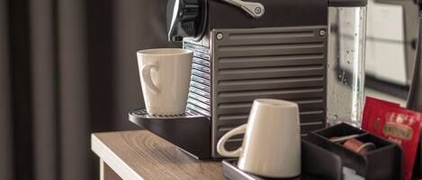 Una cafetera con dos tazas y una bandeja con un paquete de café.