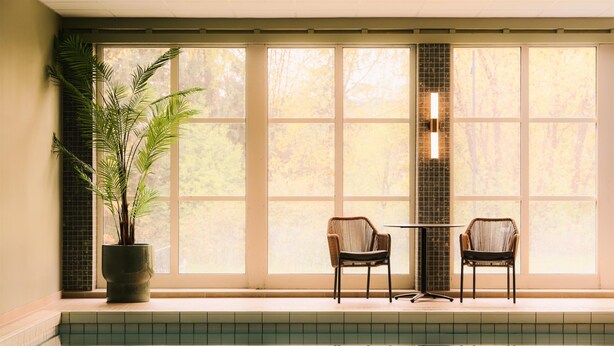 A pool area with a potted plant, two chairs, and a tiled wall. - Scandic Lillehammer Hotel (Lillehammer)