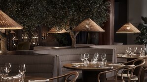 Un restaurant avec des tables rondes, des sièges rembourrés et des lampes suspendues.