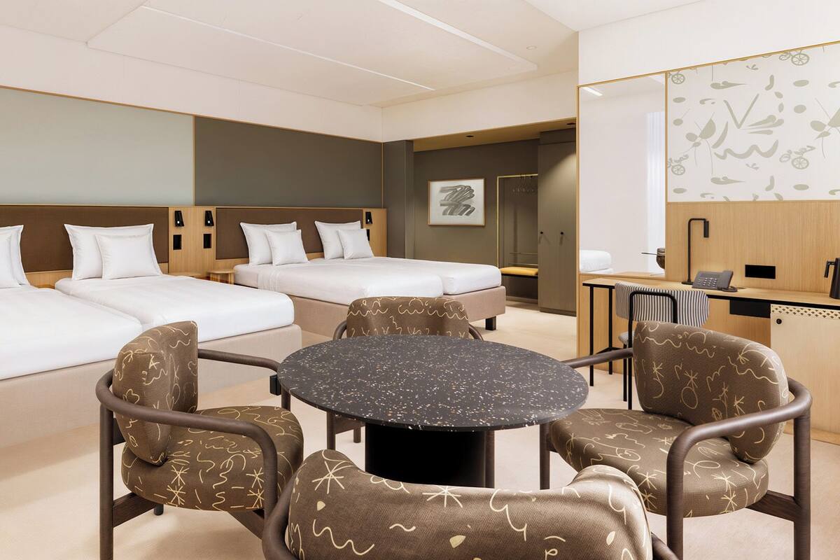 Une chambre d’hôtel avec deux lits, une table ronde et quatre chaises.