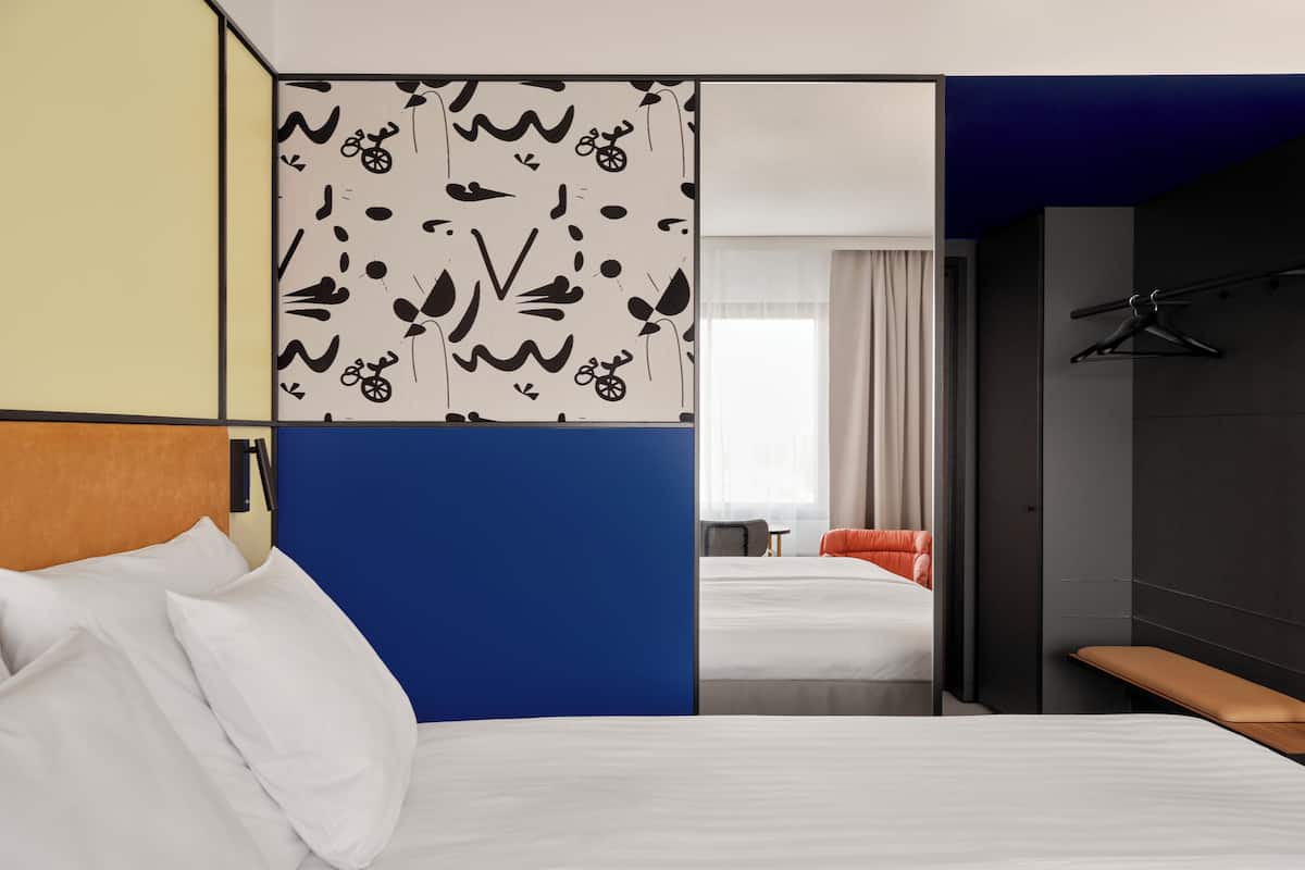 Une chambre d’hôtel avec un lit, un bureau et une vue sur une autre chambre.