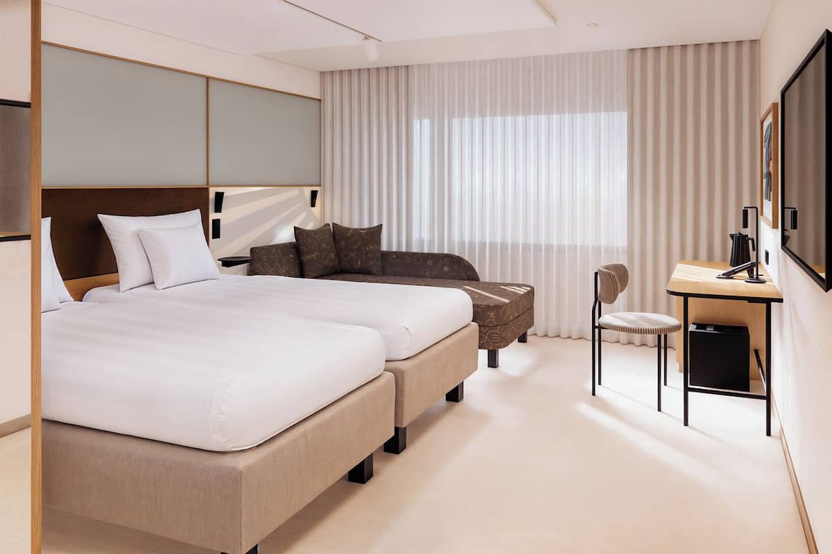 Une chambre d’hôtel avec un grand lit, un bureau, une chaise et un téléviseur.