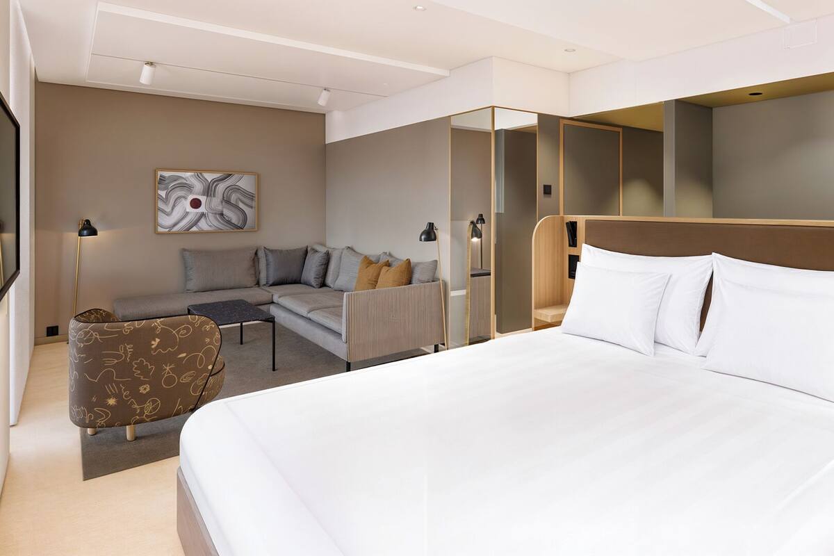 Une chambre d’hôtel moderne, dotée d’un grand lit, d’un canapé, d’un fauteuil et d’un bureau.