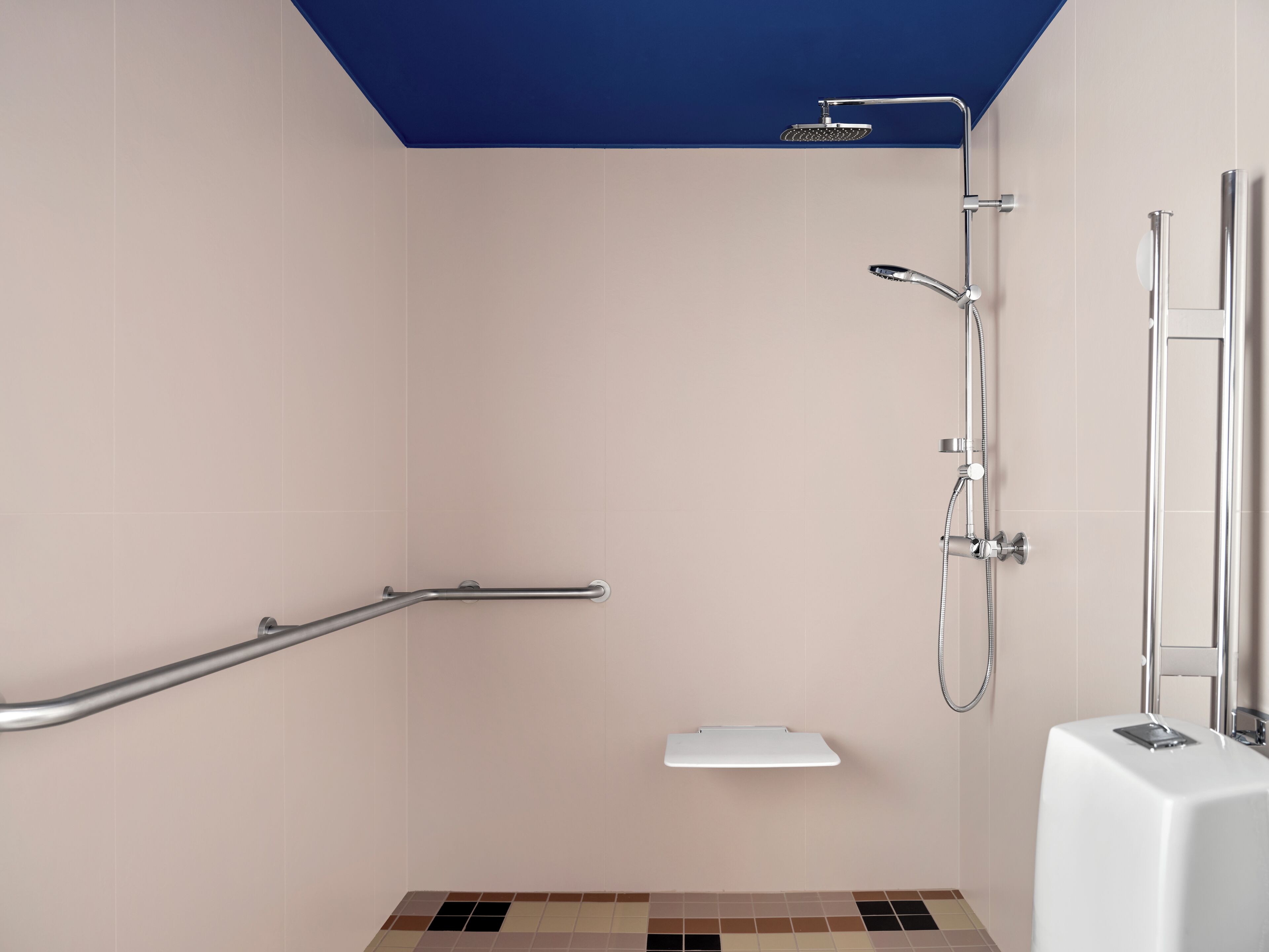 A modern bathroom with a walk-in shower, grab bars, and a white pedestal sink.