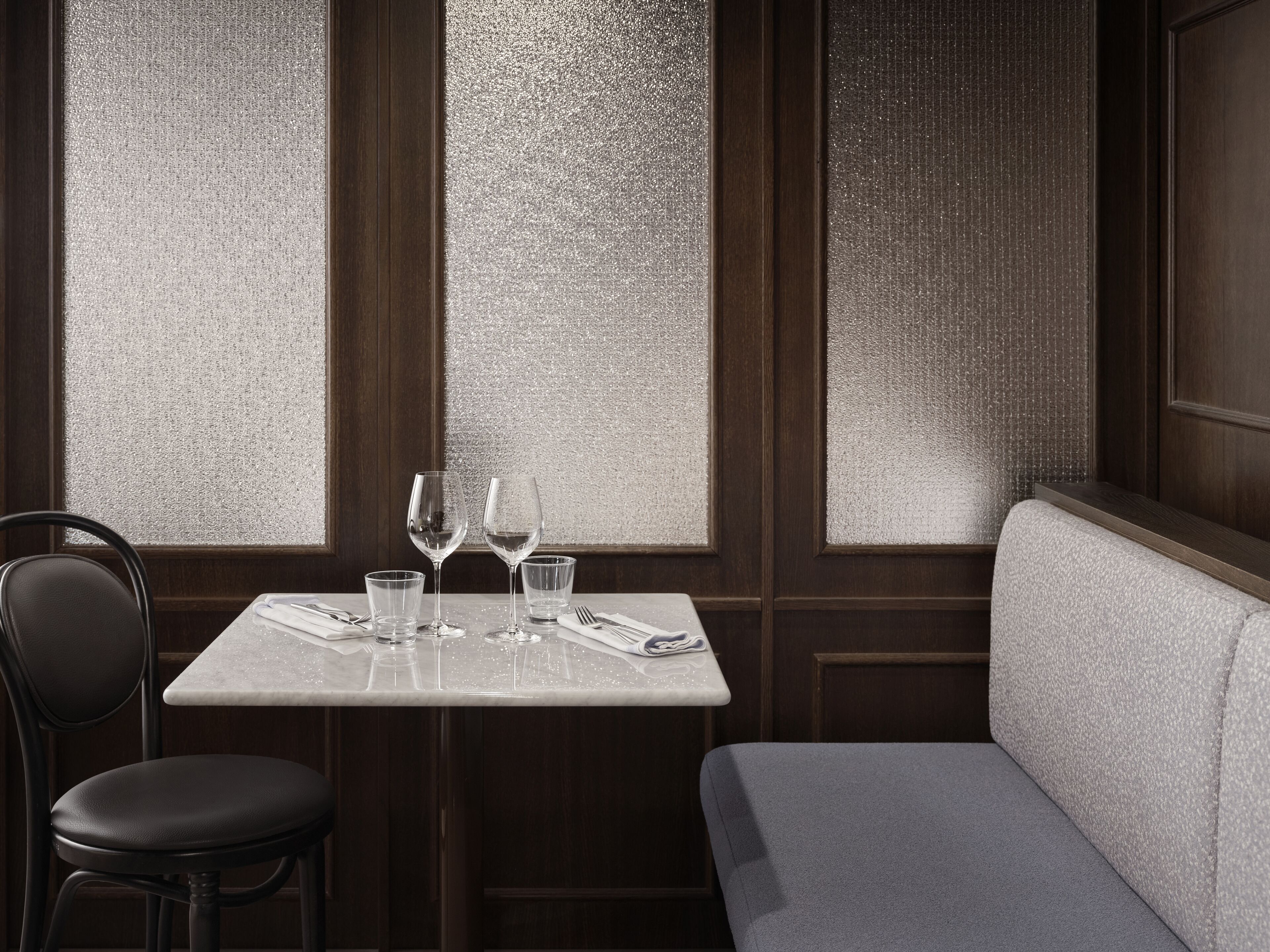 A dining area with a table set for two, two wine glasses, and a chair.
