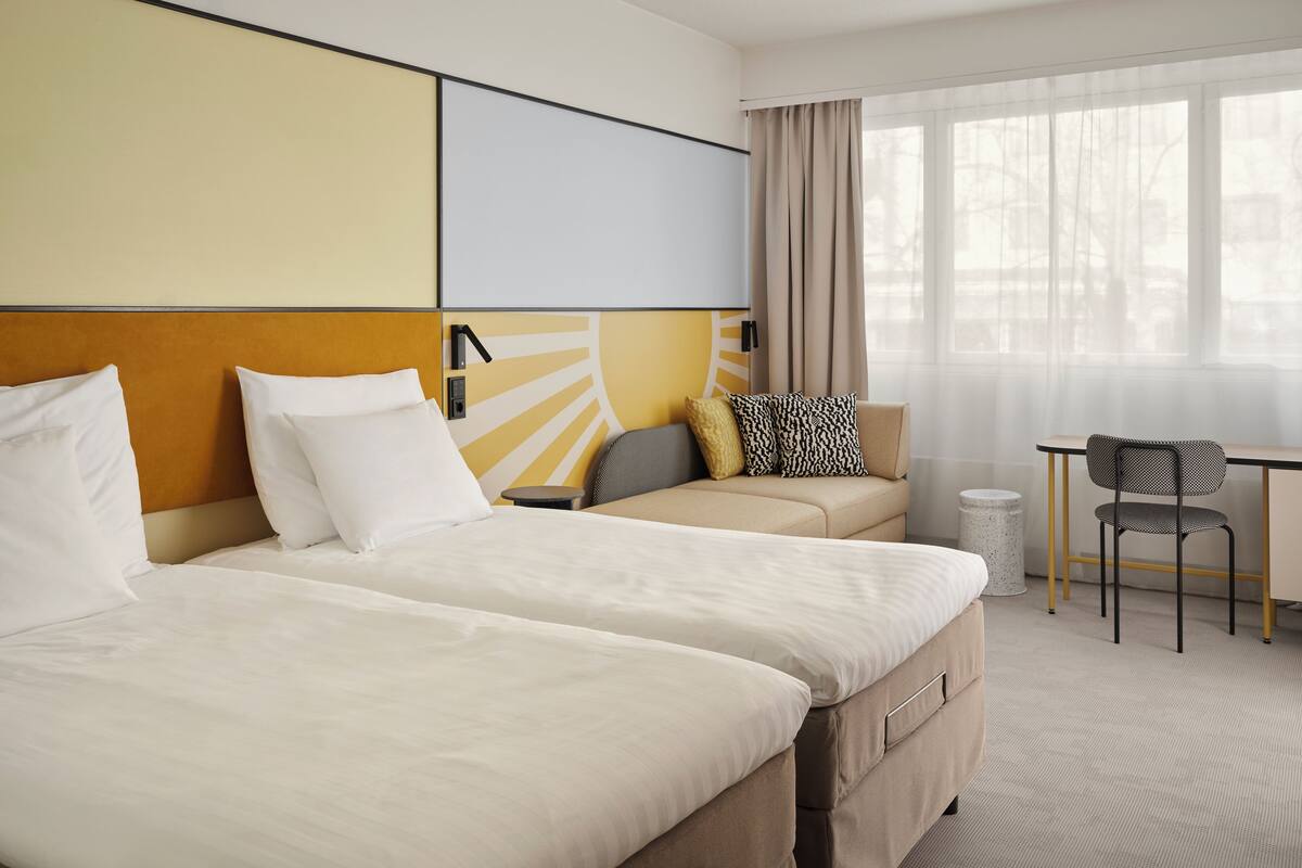 Habitació d'hotel amb dos llits, un sofà, un escriptori i una cadira.