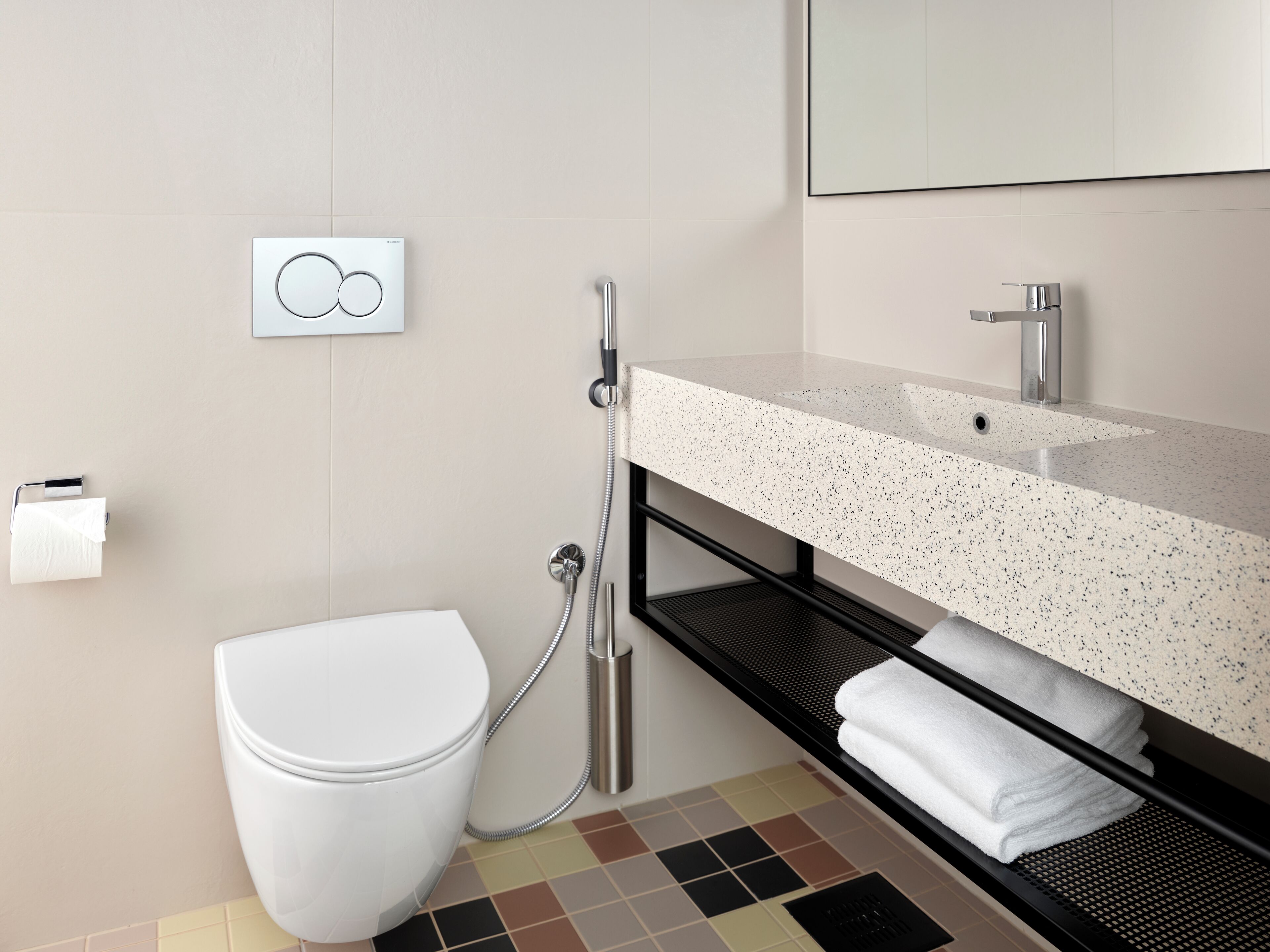 A modern bathroom with a toilet, a shower, a sink, and a towel rack.