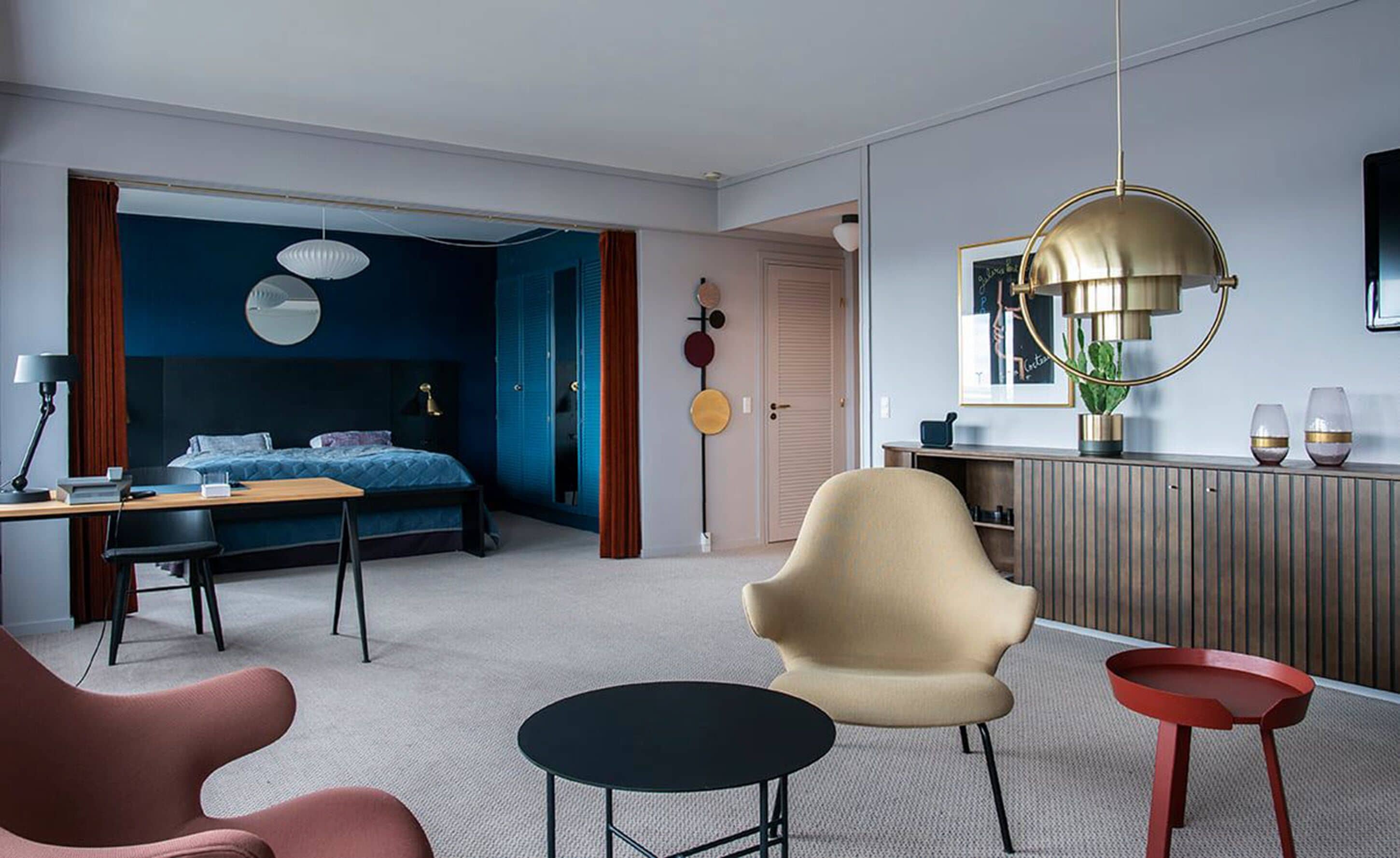 A modern bedroom with a bed, a desk, a chair, and a round table.