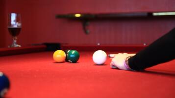 A red pool table with four billiard balls and a cue stick.