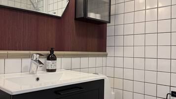 A bathroom with a white sink, black cabinet, and a mirror.